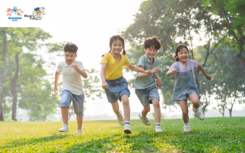 ALT Text: group of children energetically running through a vibrant park filled with trees and open space