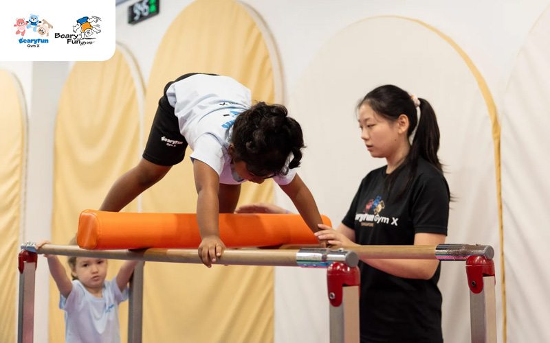 Child balancing on bar with instructor’s help.