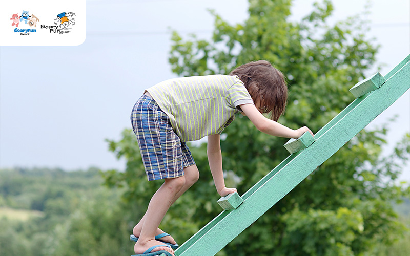 Child cautiously climbing a short ladder outdoors.