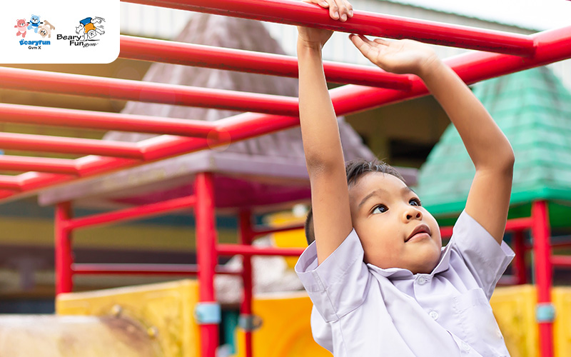 Child hanging on monkey bars, improving motor skills.