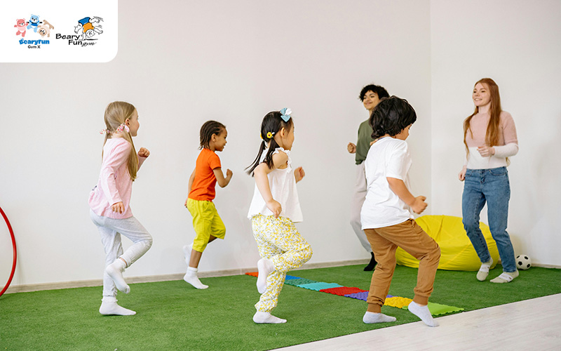 Children playing in a preschool gym with an instructor.