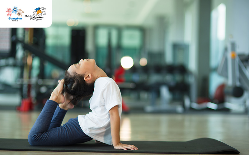 Girl performing a bridge pose on a gymnastics mat.