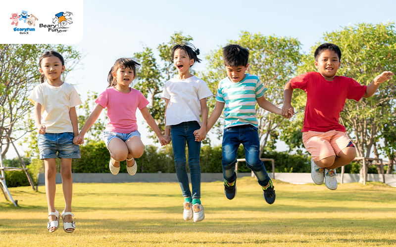 Kids jumping and playing outside on grass.
