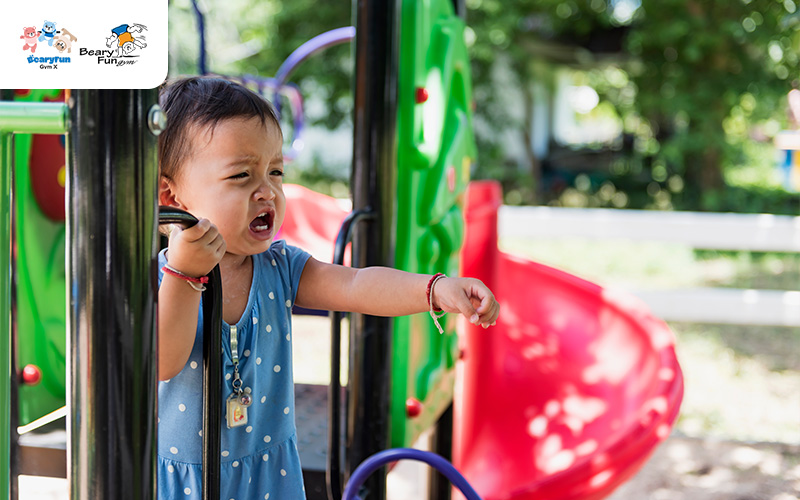 Young child showing distress on a playground structure.