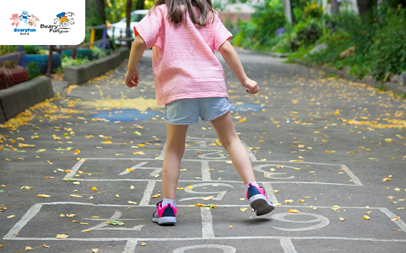 Child balancing while playing hopscotch.