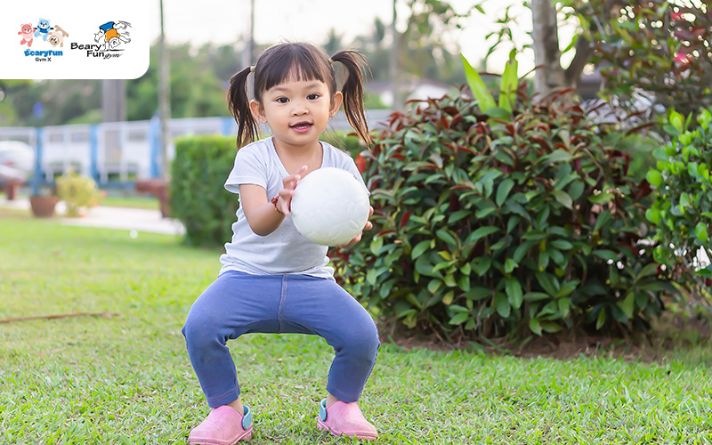 Child struggling to catch a ball.
