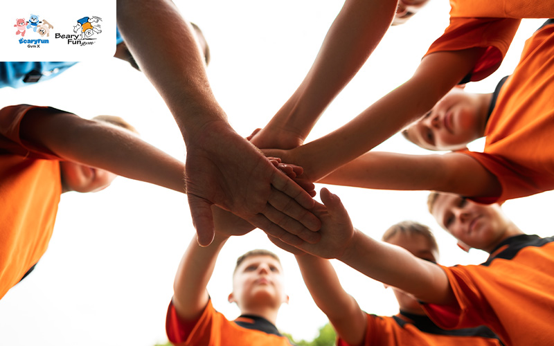 A team of young players with hands stacked together.