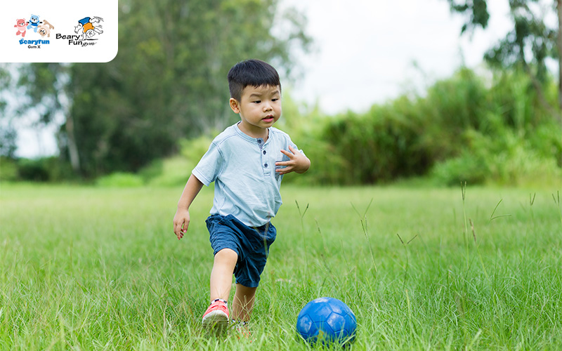 A young boy kicking a blue soccer ball.