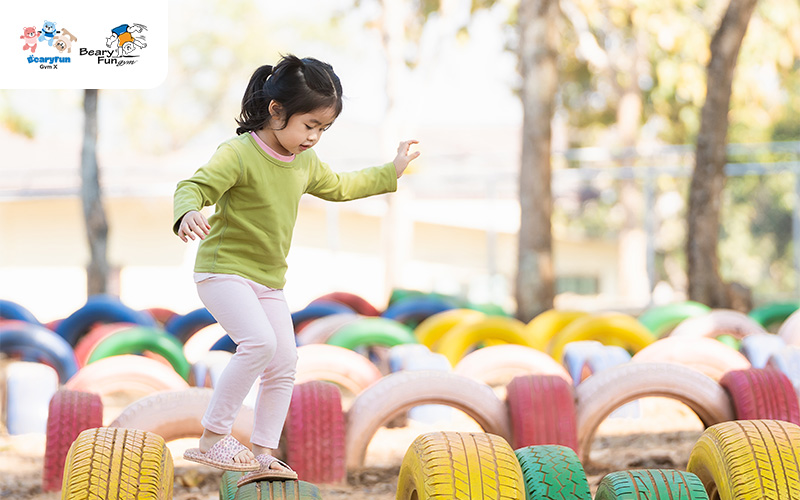 A young girl carefully balancing on a row of tires.