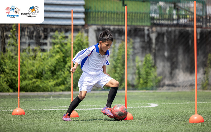 Boy dribbling a soccer ball during a training drill.