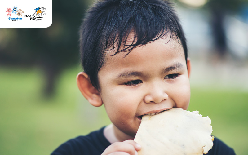 Child is sweating and eating a cracker at a park.