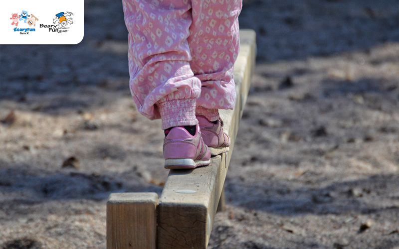 Child balancing on a wooden beam.