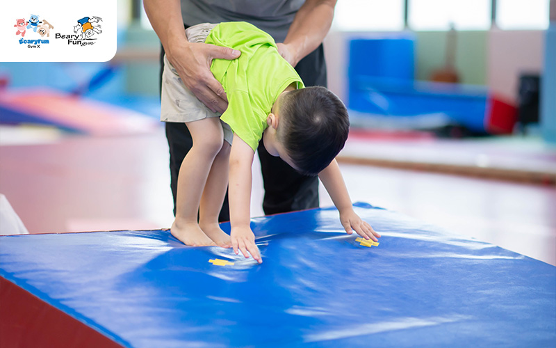 Child learning to climb in a preschool gym.