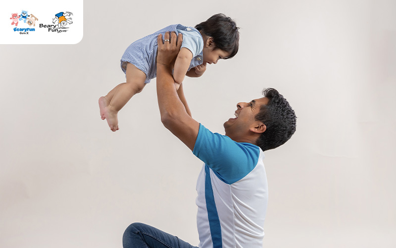 Father playing with toddler, promoting physical development.