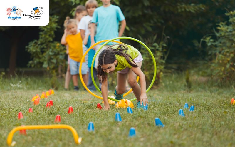 Girl crawling through a hula hoop on a lawn.