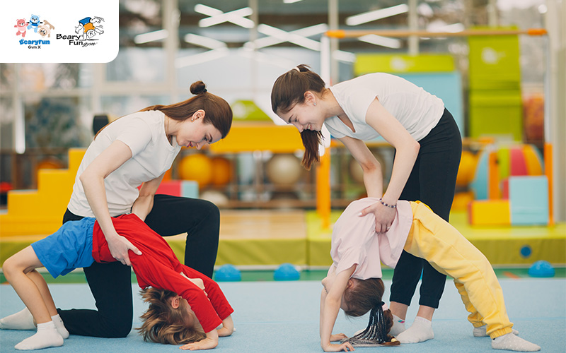 Gymnastics instructors helping two children with backbends.