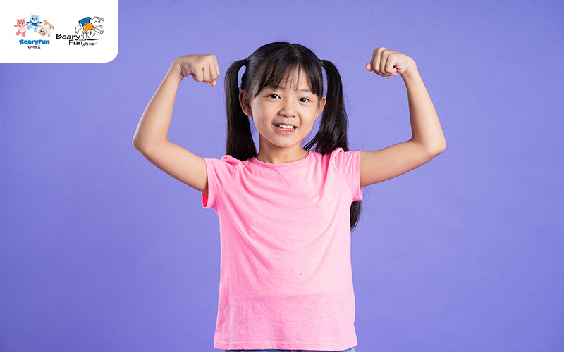 Happy child flexing muscles, showing physical development.