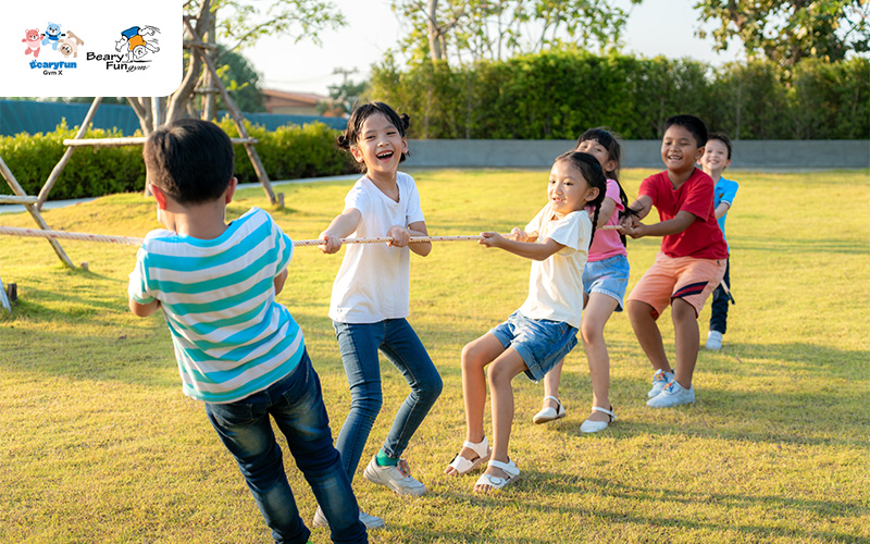 Kids playing tug-of-war on grass, having fun together.