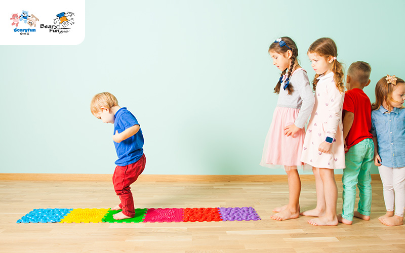 Preschoolers doing balance drills on textured floor mats.