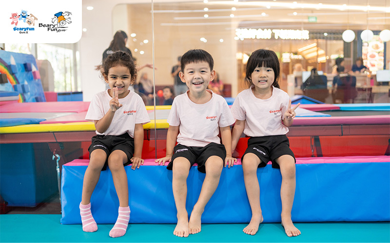 Three children playing and smiling in a gym.