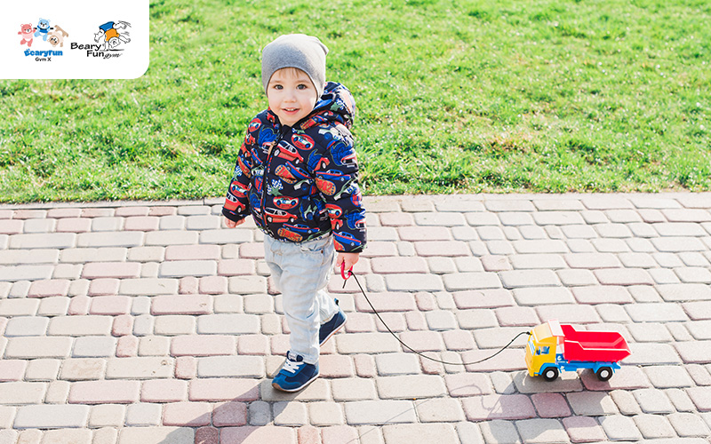 Toddler pulling toy truck, aiding physical development.