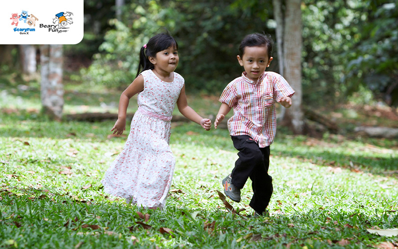 Two young children running happily in a park.
