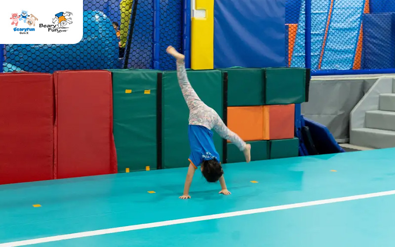 Young girl doing a cartwheel on a tumbling mat.