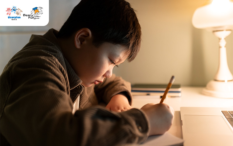 Young boy diligently studying and writing at a desk.
